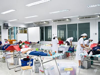 ภาพบรรยากาศของเหล่าพนักงานบริจาคเลือดที่นอนอยู่บนเตียงโดยมีแพทย์จากโรงพยาบาลบางประกอก 9 เจาะเลือดอยู่ข้างเตียง
