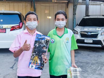 ลูกของพนักงาน เอ.เบสท์ อินเตอร์ โปรดักส์ ยืนถือของขวัญจับฉลากในกิจกรรมวันเด็กแห่งชาติ 2566
