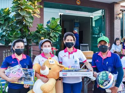 พนักงาน เอ.เบสท์ อินเตอร์ โปรดักส์ ยืนถือของขวัญจับฉลากในกิจกรรมวันเด็กแห่งชาติ 2566